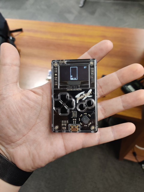 A hand holding a ArduBoy, a tiny games console 