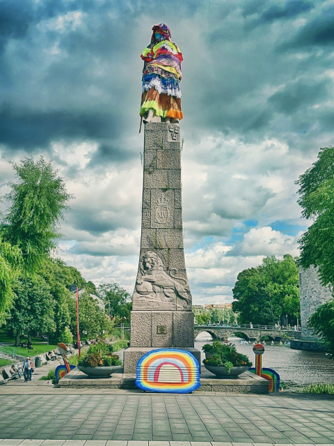 An art installation on top of a statue. It has been dressed and coloured in all the colours.