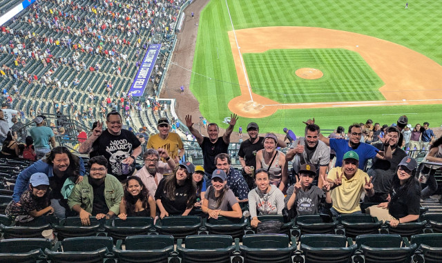 Group photo of GUADEC attendees at Coors Field with baseball pitch in the background 