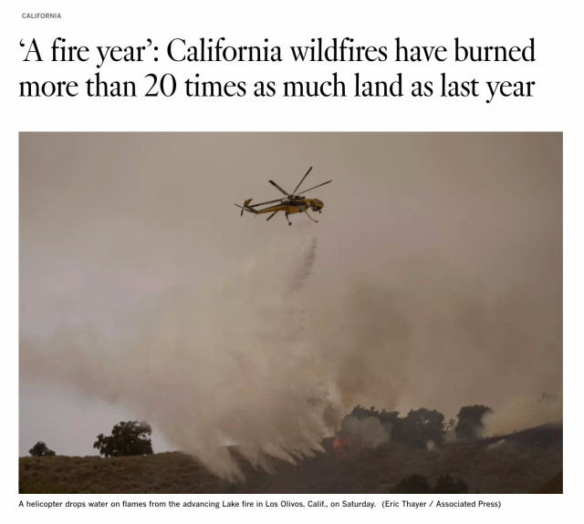 Screenshot from top of linked article. Headline says: "California wildfires have burned more than 20 times as much land as last year." Below this is a photo of a helicopter dropping water on flames from a fire near Los Olivos, California.
