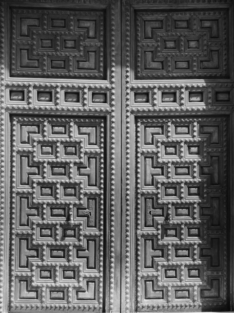 Black and white image showing an ornate Málagan door featuring interlocking rectangular designs with shell-like studding