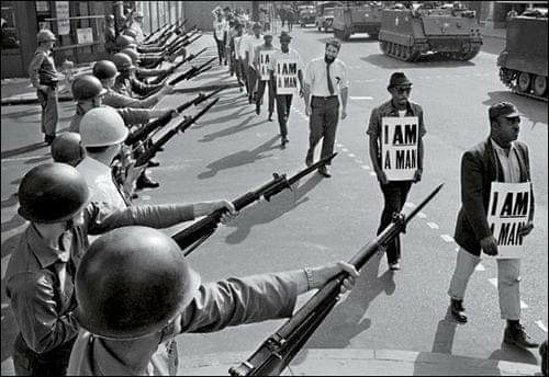 National Guard troops lined Beale Street, Memphis, during a protest on March 29 , 1968. Black protesters wear signs saying "I AM A MAN".