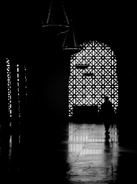 A man is cast into silhouette by the bright light coming in through an ornate Muslim-period window at Córdoba's beautiful Mezquita-Cathedral