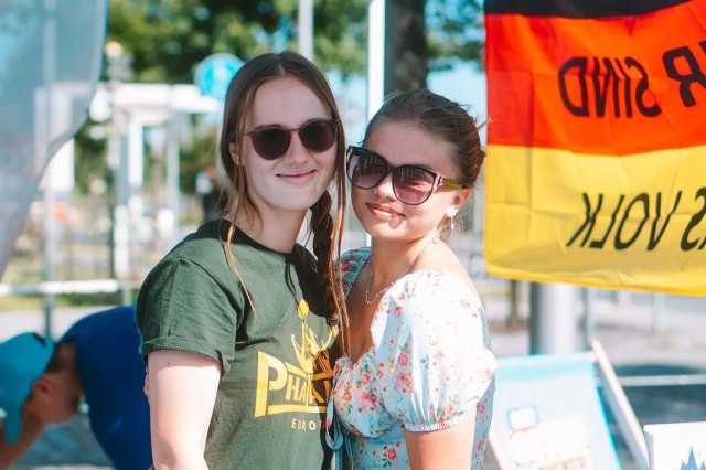 Carolin Lichtenheld und Candy Jacobs posieren Wange an Wange auf einer AfD-Wahlkampfkundgebung in Sonneberg im August 2024. Lichtenheld trägt ein dunkelgrünes Shirt mit der Aufschrift „Phalanx“.