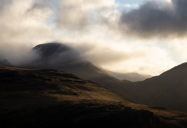 A Lakeland mountain breaks free of cloud cover as late afternoon sun catches the clouds. 