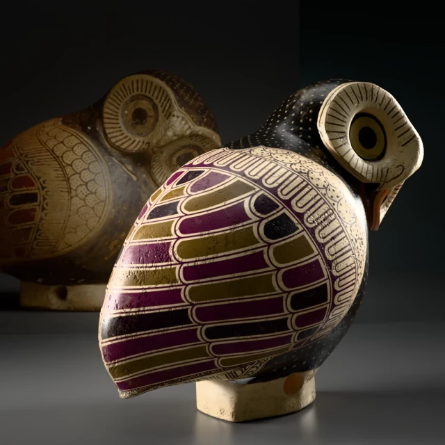 Back and right view of an ancient Greek aryballos in the shape of a tiny owl with ochre, purple and black decor mimicking feathers and white dots on the head. Eyes are round with ochre pupils and surrounded by converging lines.  On the back is a picture of the original object the 3D model is inspired from.