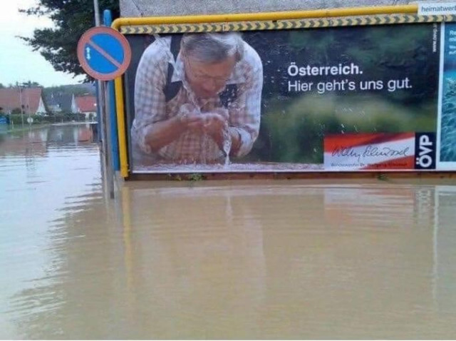 Foto eines alten Wahlplakats der ÖVP: Wolfgang Schüssel (mit Wanderrucksack) beugt sich vor und trinkt gerade Wasser aus seinen Händen, daneben steht "Österreich. Hier geht's uns gut". Unter dem Plakat und rundherum ist dreckiges Hochwasser, es sieht aus, als würde er direkt daraus trinken.