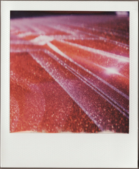 Polaroid close-up of the red metal flake paint and stripes on the hood of a Continental.