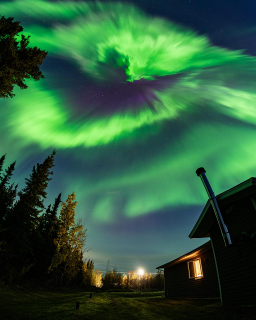 Photograph from source in toot showing bright green aurora in the night sky. There is a bat-like shaped area of the aurora. 