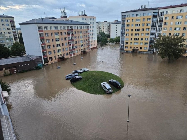 A flooded residential area with several buildings and submerged cars. An island of grass is visible amidst the water, surrounded by cars partially submerged. The scene reflects the aftermath of heavy rainfall or flooding.

#source #internet 