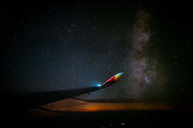 A photograph of the right wing of an Asiana Airlines A350. The lines of the wing and the wingtip lead to the Milky Way which can be seen rising straight up from the horizon next to the A350's wingtip.