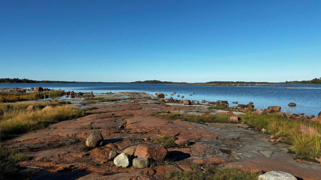 Picture of the red cliffs of the Åland Islands archipelago on a windless, sunny day in autumn.