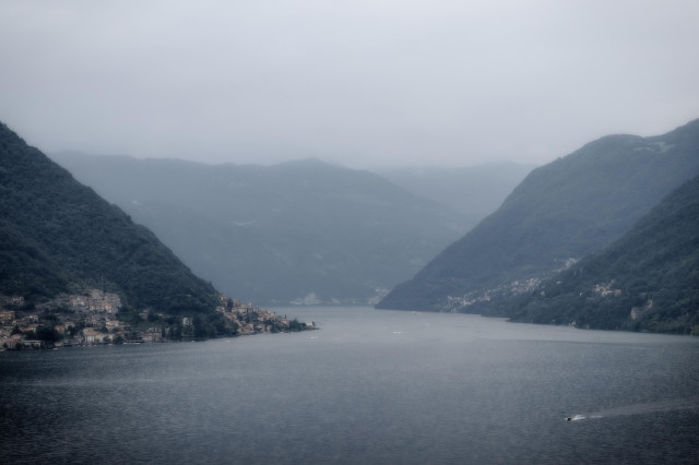 Fotografía donde se ve parte del lago de Como (Italia) en un día gris con cierta bruma en la parte superior.