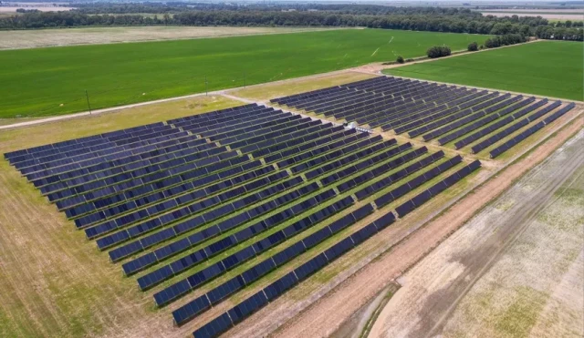 aerial photo of a large solar farm in a flat green landscape 