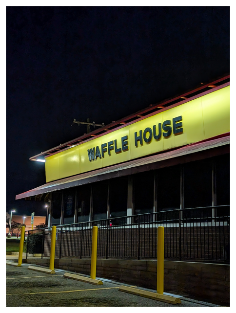 night waffle house exterior is lit, but the restaurant is dark inside. no evidence of humans in this image.