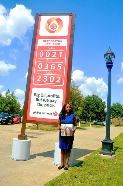 Carla stands with a picture of her husband Eugene in front of a sign that reads:

Heat Deaths Last Year

Dalls: 21
Texas: 365
USA: 2302

Big Oil profits. But we pay the price.

global witness