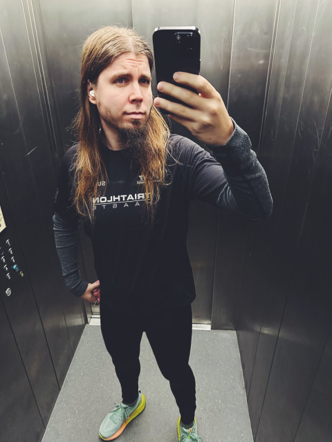 Selfie from the elevator mirror. I have a long hair (male) and wearing running clothes and fancy running shoes.