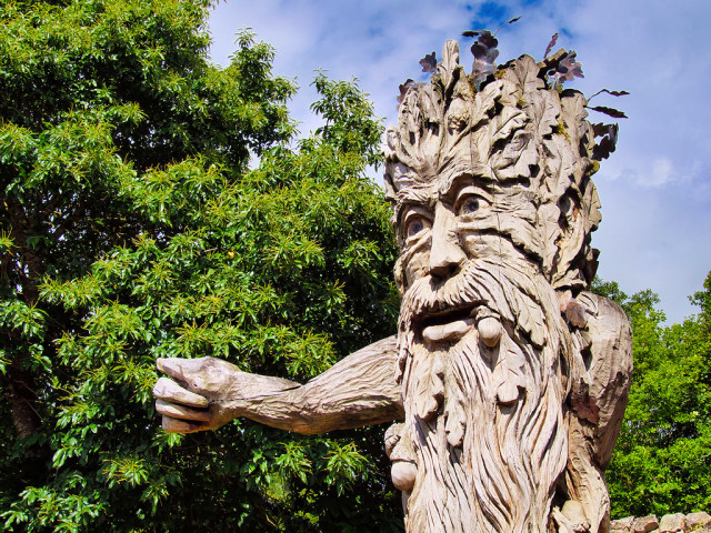 Giant carved from wood, with a 'green-man'-like face and head covered in leaves and foliage.