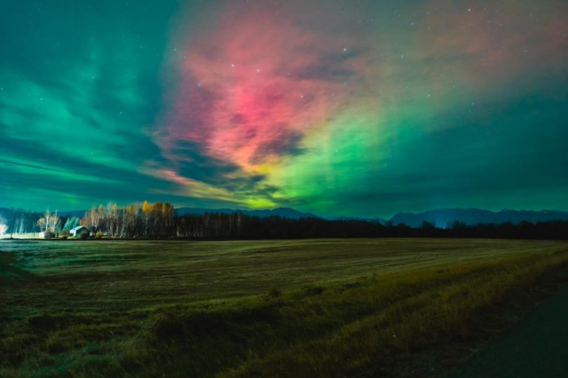 Stunning shot of the Northern Lights over a field in Palmer, Alaska in green, yellow and red.