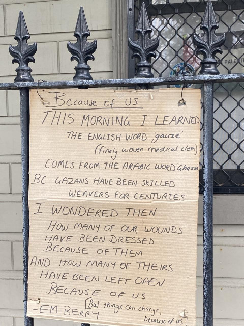 Photo of a cardboard sign up on a wrought iron fence. The handwritten words quote a poem Because of Us by Em Brown which is about Gaza. Sorry about the ALLCAPS in advance, it's how the sign is written though not the original poem.

Because of Us

THIS MORNING I LEARNED, THE ENGLISH WORD gauze (finely woven medical clom) 

COMES FROM THE ARABIC WORD' Ghazza 

BC GAZANS HAVE BEEN SKILLED WEAVERS FOR CENTURIES 

I WONDERED THEN HOW MANY OF OUR WOUNDS HAVE BEEN DRESSED BECAUSE OF THEM 

AND HOW MANY OF THEIRS HAVE BEEN LEFT OPEN BELAUSE Of US [But things can change, because of us]

- EM BERRY 