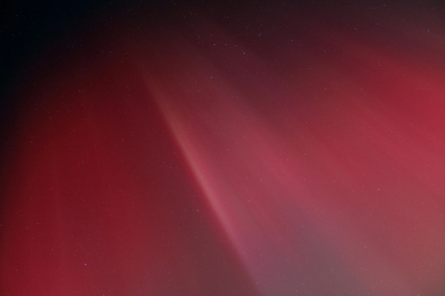 Red pillars converging at the zenith in a bright coronal aurora display