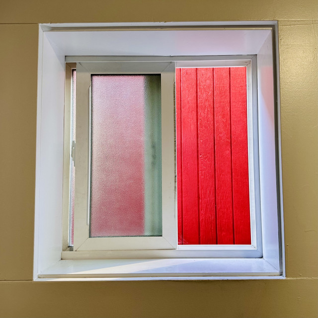 A digital photo of a square window with red and frosted glass. Pretty symmetrical. The red has interesting textures