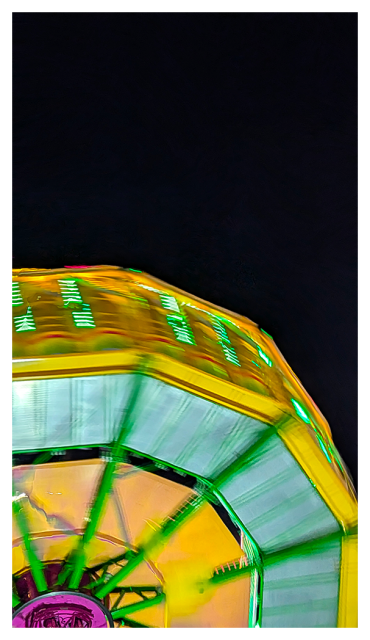 night. low angle view. of a carnival ride with motion blur against a black sky.