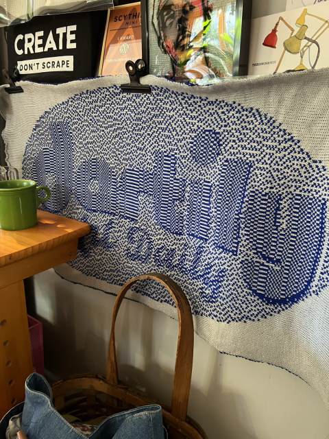 Photo of knit fabric banner in blue and gray that says “dartily: Art Daily”