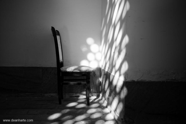 A chair in a corner of a mosque bathes in beautiful light patterns