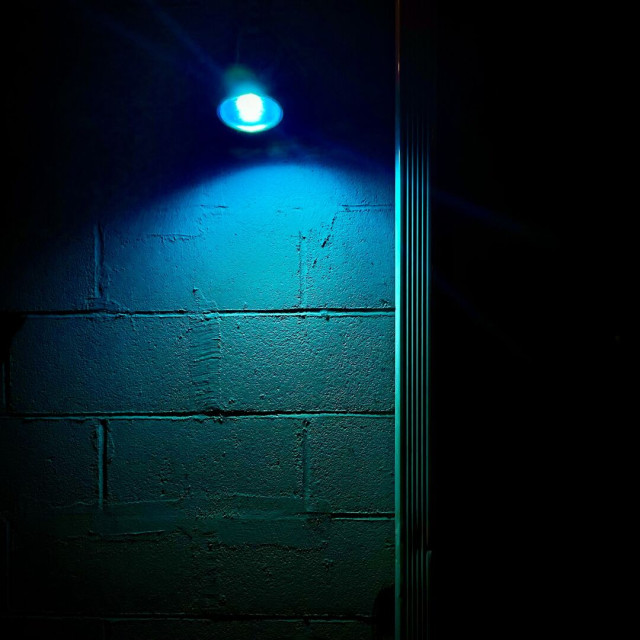 Blue light shining on a concrete block wall at nighttime.