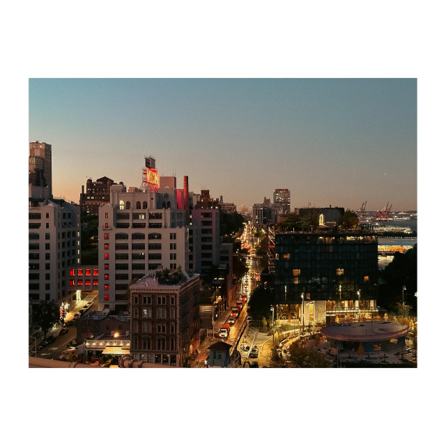 A photo of Brooklyn from the Brooklyn Bridge. It’s early morning and the lights are all on. The sky is pinkish and light blue. 