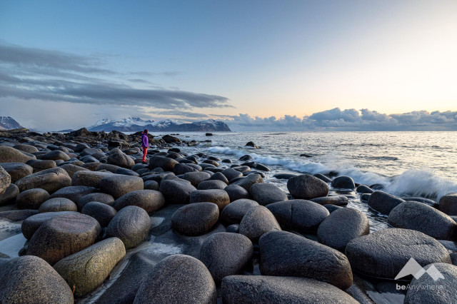 Small woman between large stones at the coastline on the Lofoten Islands.