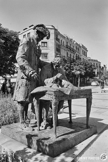 A black-and-white film photo of a statue of the Baroque architect Albert de Churriguera who designed Plaza Mayor with the Third Count of Francos - José del Castillo y Larrazabal. The statue is at Plaza del Poeta Iglesias just south of Plaza Mayor.