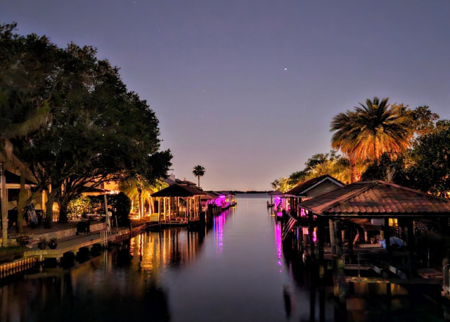 Overlooking a waterway lined with the warm glow of piers and docks reflecting upon the calm dark water below.