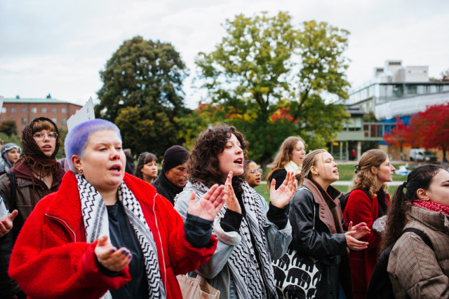 A group of protesters clapping and shouting slogans.