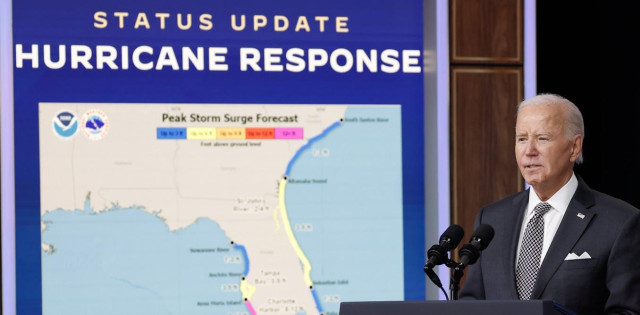 A man in a suit at a lectern next to a sign that says 'STATUS UPDATE HURRICANE RESPONSE' above a map of the state of Florida.