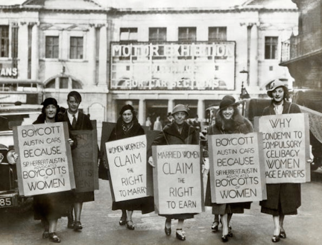 Six women outside the Olympia exhibition hall in London, carrying placards calling for a boycott of Austin.