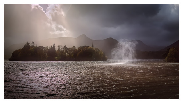 A tornado starts to form on a lake, the sun catching it as it rises up. Shafts of light fall on an island masking the mountains in the background