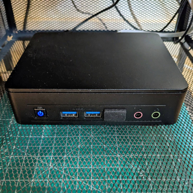 A small dusty server in a wire drawer with some cables in the background.