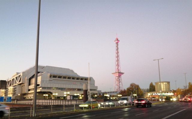 Dawn in Berlin.

The exhibition area. To the left a futuristic building from Aluminium, in the center a radio tower from steel, lighted in several colours.

To the right a round building in rhe simplistic style of the 1930s. 