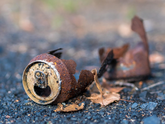 Zerbrochene, verrostete Getränkedose auf Asphalt. Nahaufnahme.