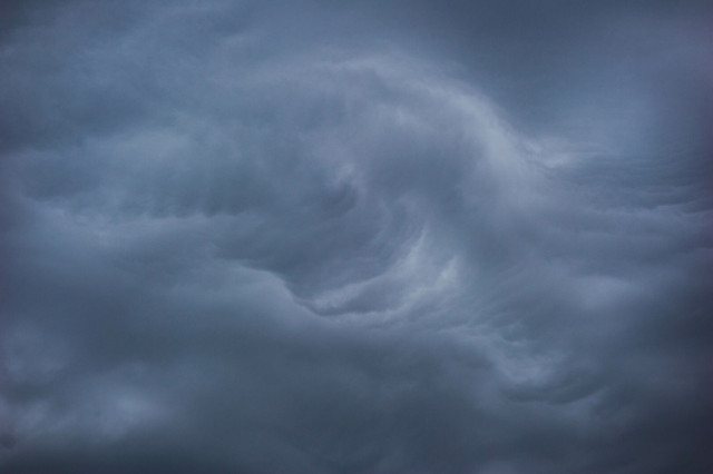 Photo of unsettled cloud cover, in middle of which is a broken curl or a twist, or a ghost, or a Hokusai wave facing back towards set of flight feathers; dark troughs around the edge of the frame.