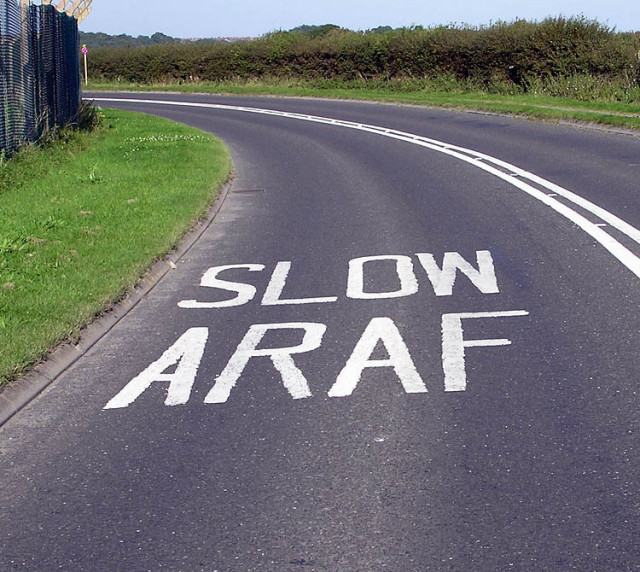 A bend in the road. The road markings read, SLOW ARAF.