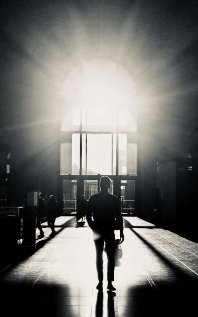 Silhouette of a person in blackandwhite. Sunlight coming through a window in the background.