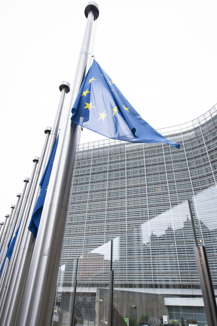 Close up of a European flag at half mast in front of the facade of the Berlaymont building in Brussels.