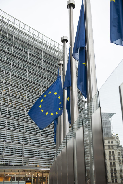 Close up of a European flag at half mast in front of the facade of the Berlaymont building in Brussels.