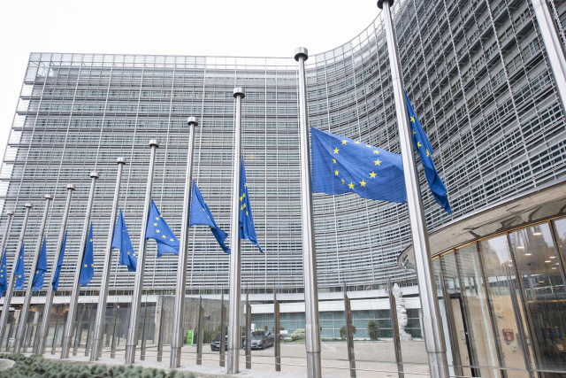 A series of 11 European flags at half mast in front of the facade of the Berlaymont building in Brussels.