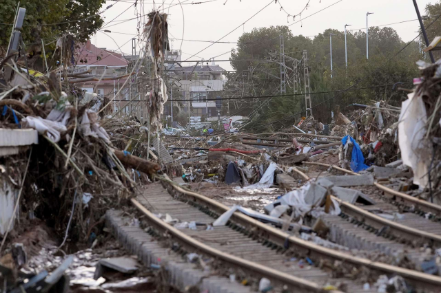 Foto:  Angeschwemmter Müll auf Bahngeleisen
AP/Alberto Saiz
Von Überschwemmungen zerstörte Zugsstrecke in der Region Valencia

_____________________
Unzählige Straßen verwandelten sich blitzschnell in reißende Ströme. Gebäude und Felder wurden unter Wasser gesetzt. Straßen, Häuser und kleinere Brücken brachen weg. Tausende Fahrzeuge wurden ineinander geschoben und zu Schrottbergen aufgetürmt.