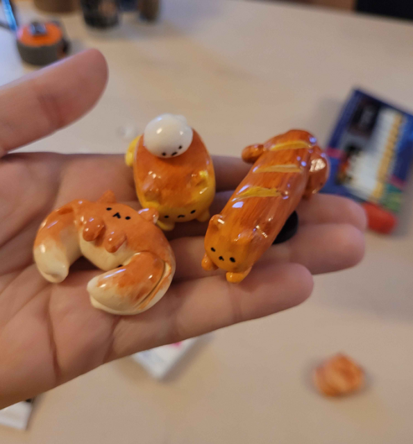 3 figure of bread shapped cat

from left to right: A croissant, a brioche with cream and a baguette