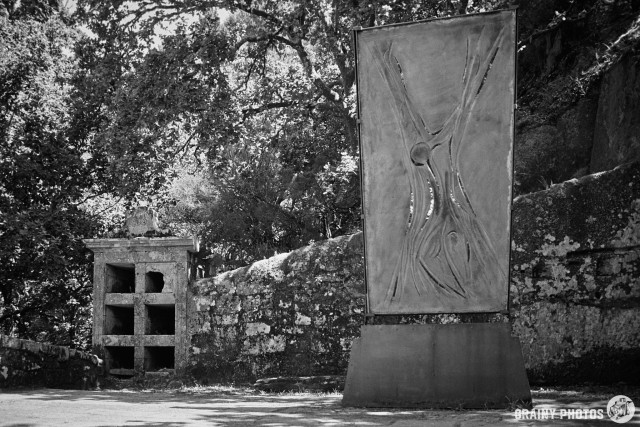 A black-and-white film photo of some of the monastery remains, and what appears to be a piece of modern art.